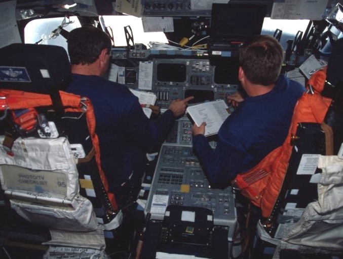 Brown, left, and Lindsey review entry checklists before donning their launch and entry suits in preparation for returning to Earth