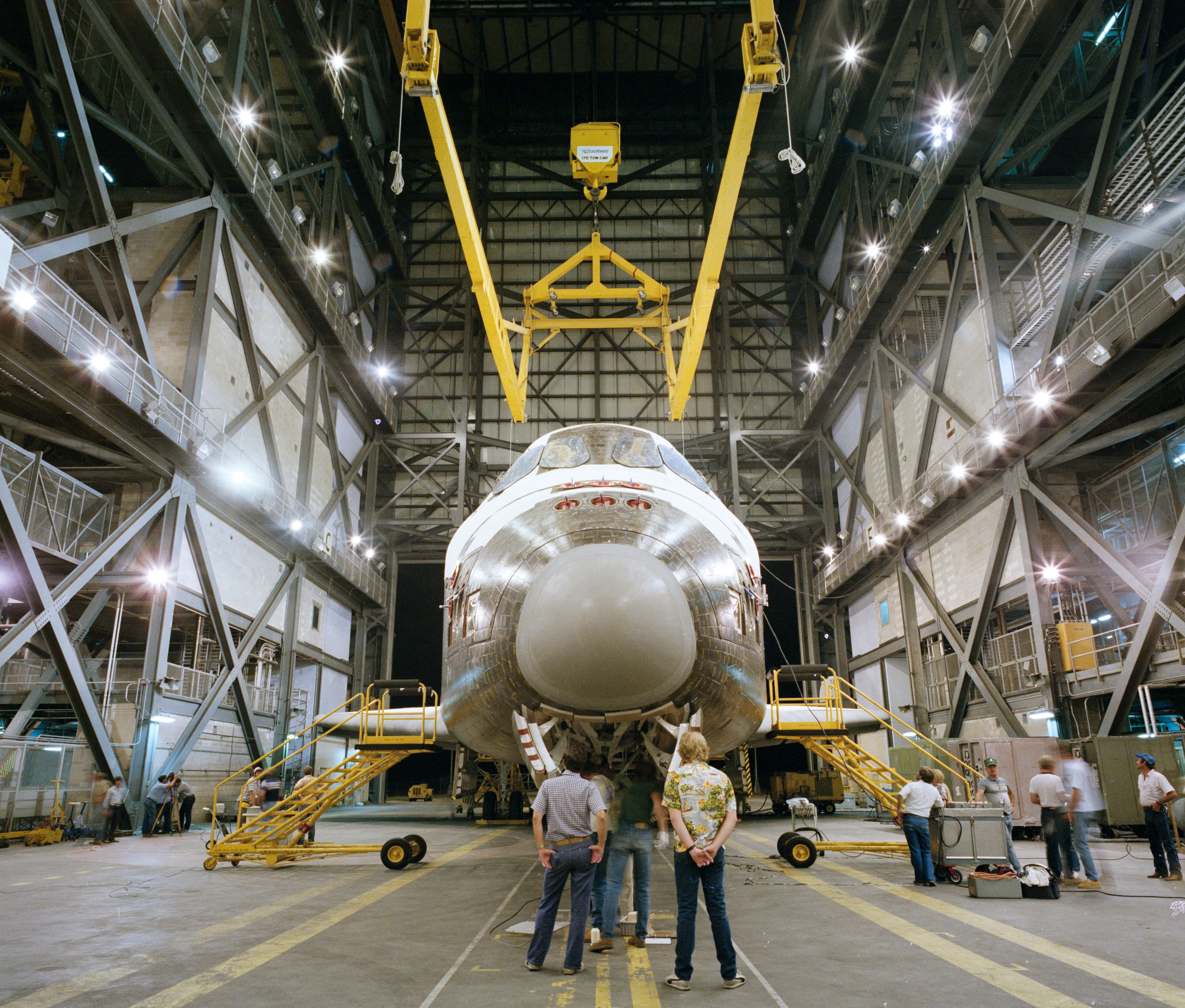 In the Vehicle Assembly Building (VAB) at NASA’s Kennedy Space Center in Florida workers prepare to lift Discovery for mating with its External Tank and twin Solid Rocket Boosters