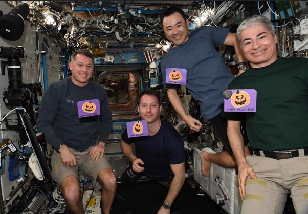 Expedition 66 crewmembers NASA astronaut R. Shane Kimbrough, left, Thomas G. Pesquet of the European Space Agency, Akihiko Hoshide of the Japan Aerospace Exploration Agency, and NASA astronaut Mark T. Vande Hei showing off their Halloween cards