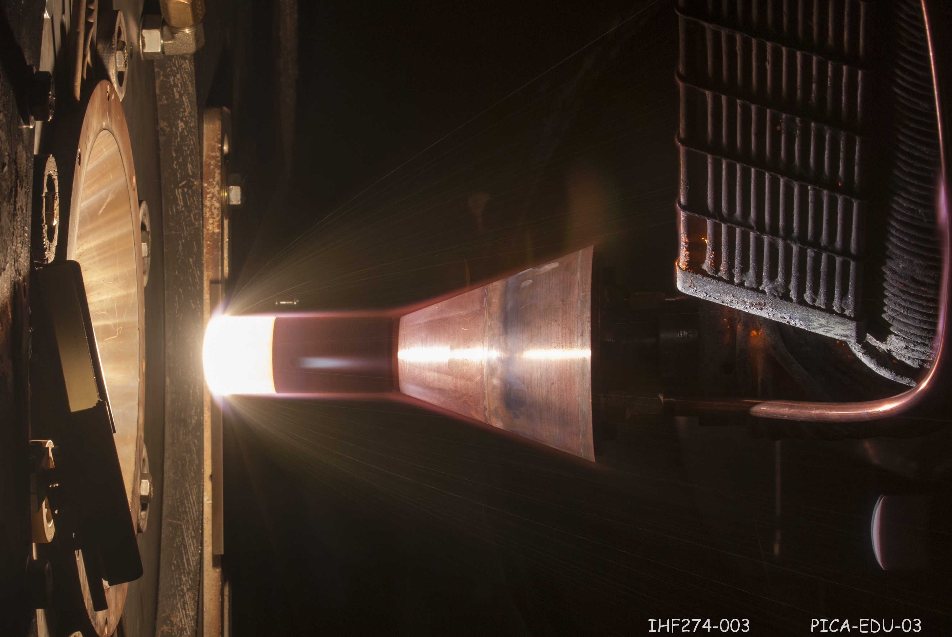 The OSIRIS-REx spacecraft's heat shield is made of a material developed at Ames: phenolic-impregnated carbon ablator (PICA). In this photo, PICA is undergoing testing in Ames' arc jet facility, which simulates atmospheric re-entry conditions, to confirm thermal protection performance for the heat shield's design.