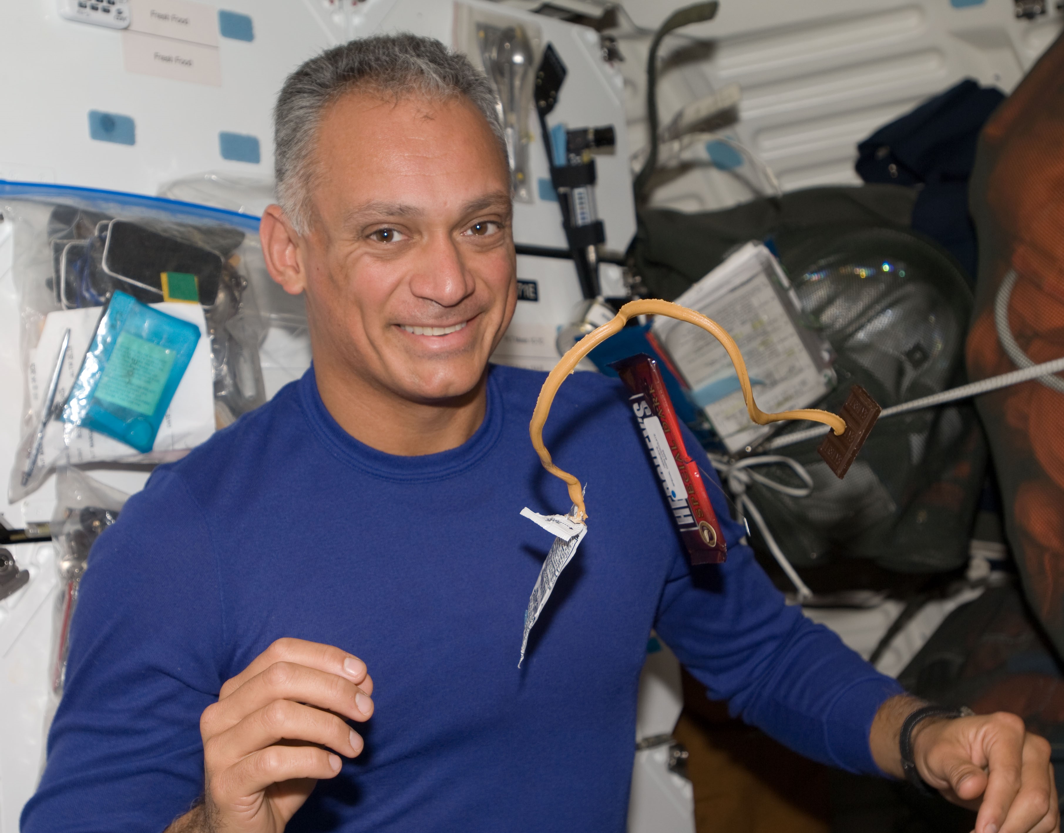 NASA astronaut John D. “Danny” Olivas eating a chocolate and peanut butter snack