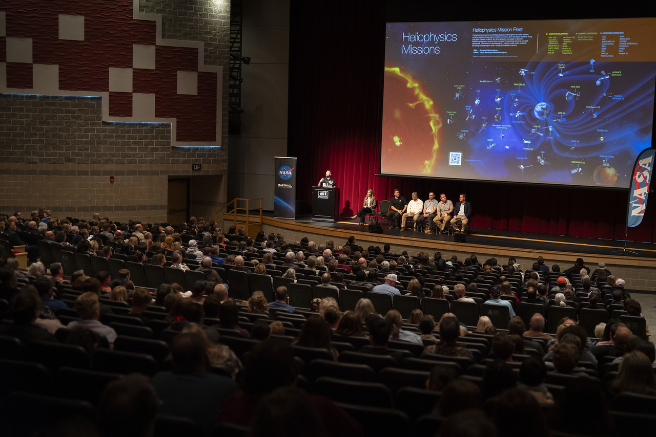 A crowd of people listen to a panel on stage discuss the 2024 eclipse.