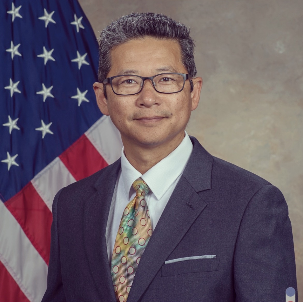 Tony Kim stands for his portrait with an American Flag behind him.
