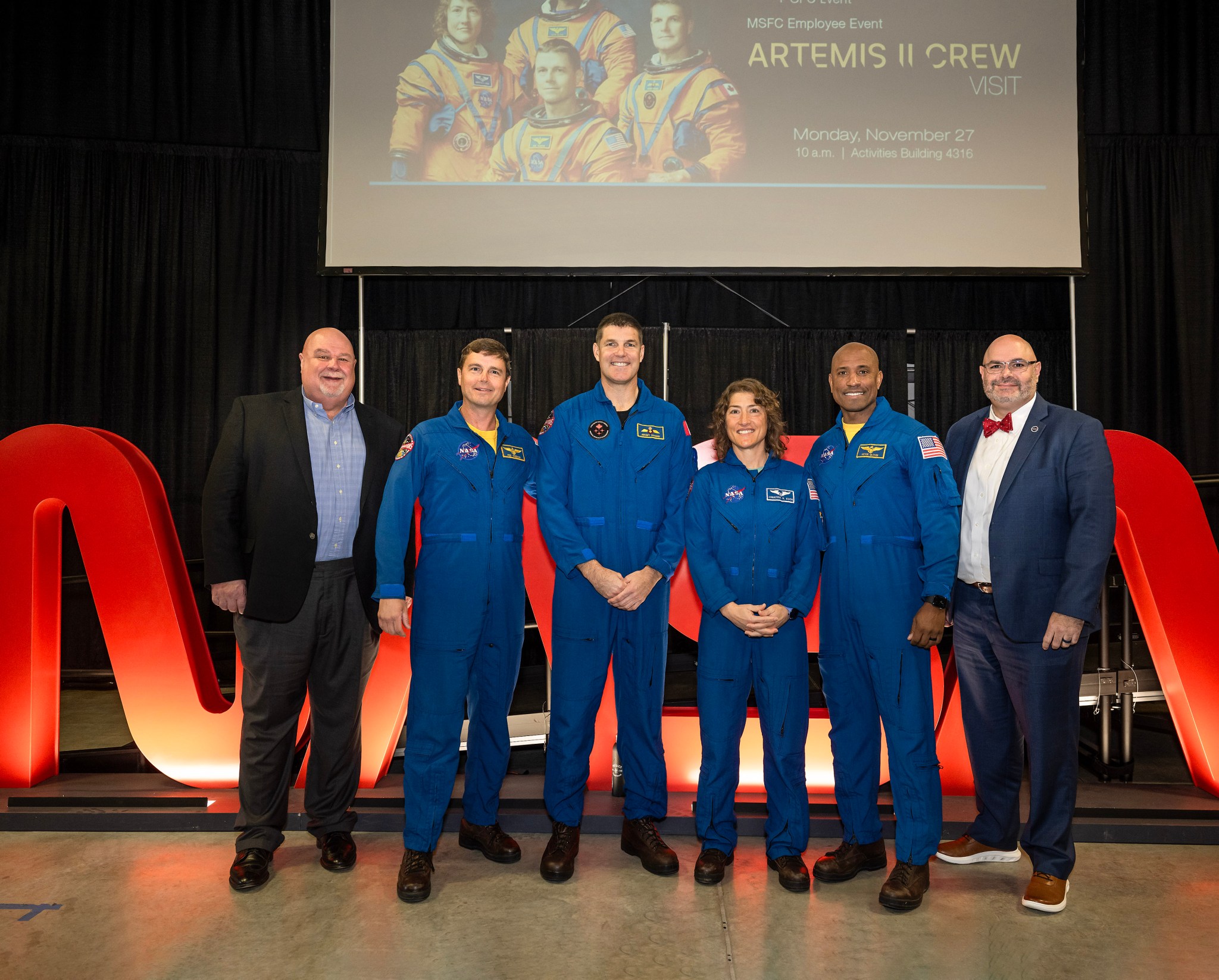 SLS Program Manager John Honeycutt, left, and acting Center Director Joseph Pelfrey, right, join the Artemis II crew for a photo at the employee event in Activities Building 4316.