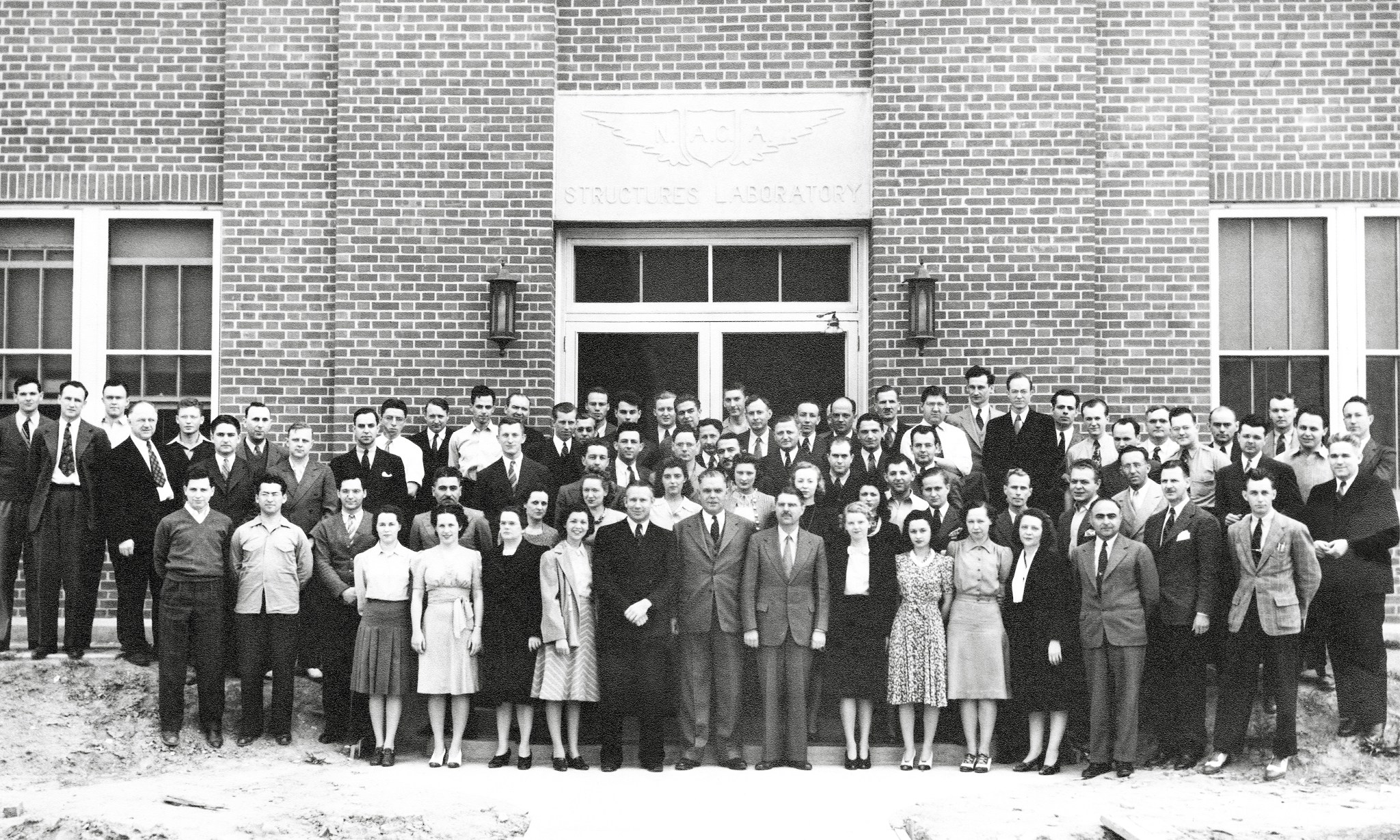 Group of people posing in front of building.