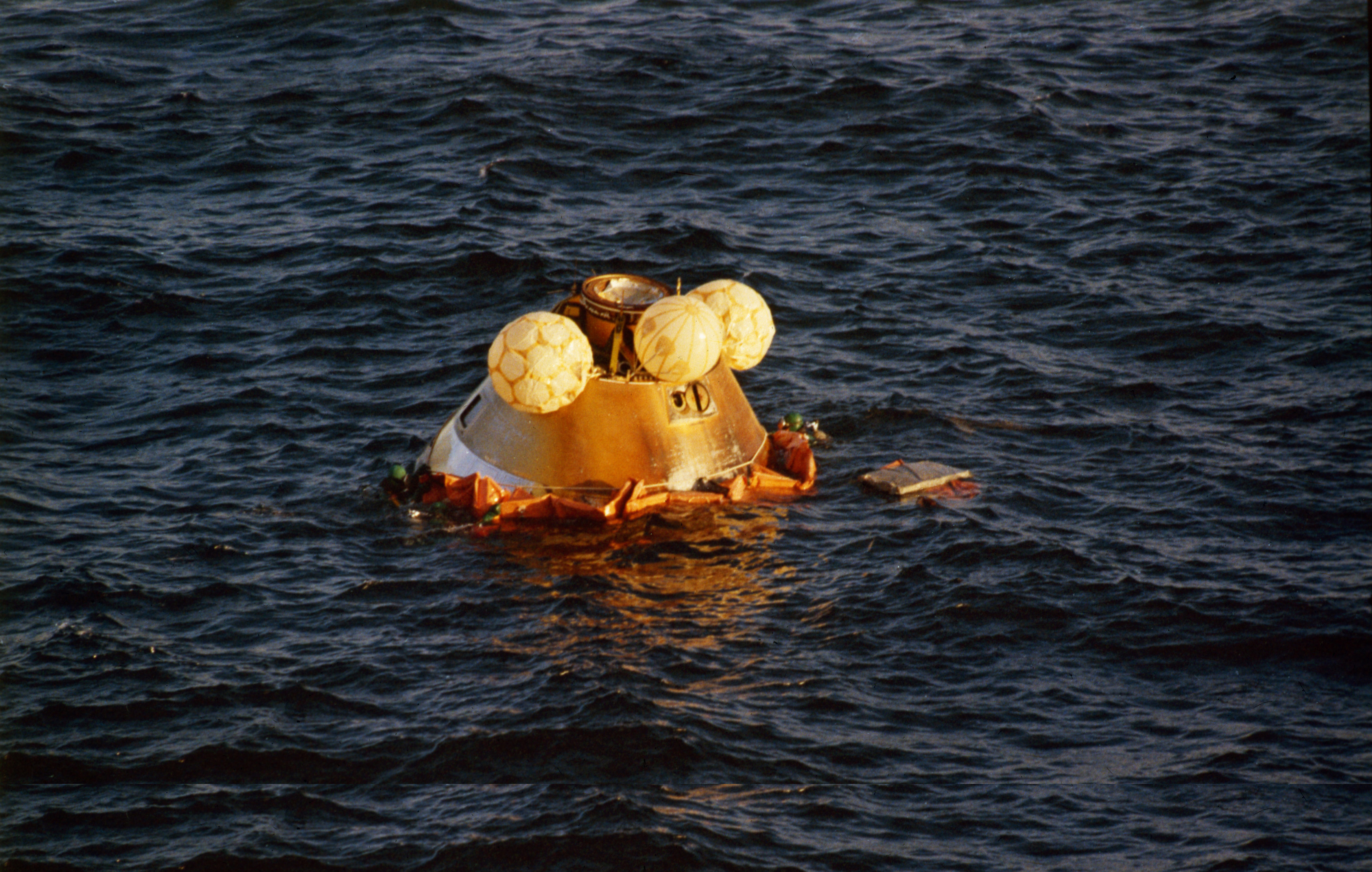 Swimmers attach an inflatable collar around the Skylab 4 Command Module (CM)