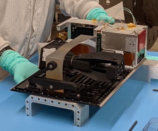 Flat board with boxes and wires attached, held by person wearing gloves