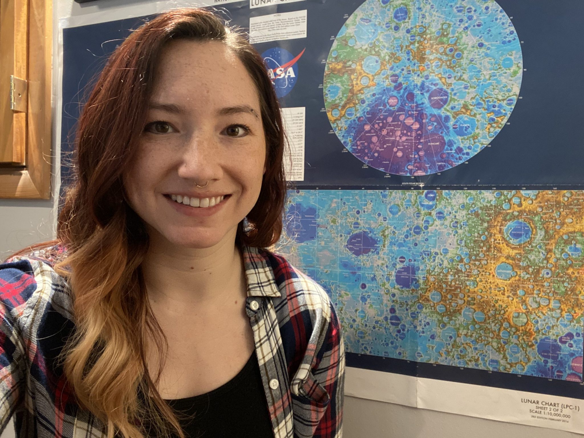 Casey Honniball stands in front of a colorful lunar map