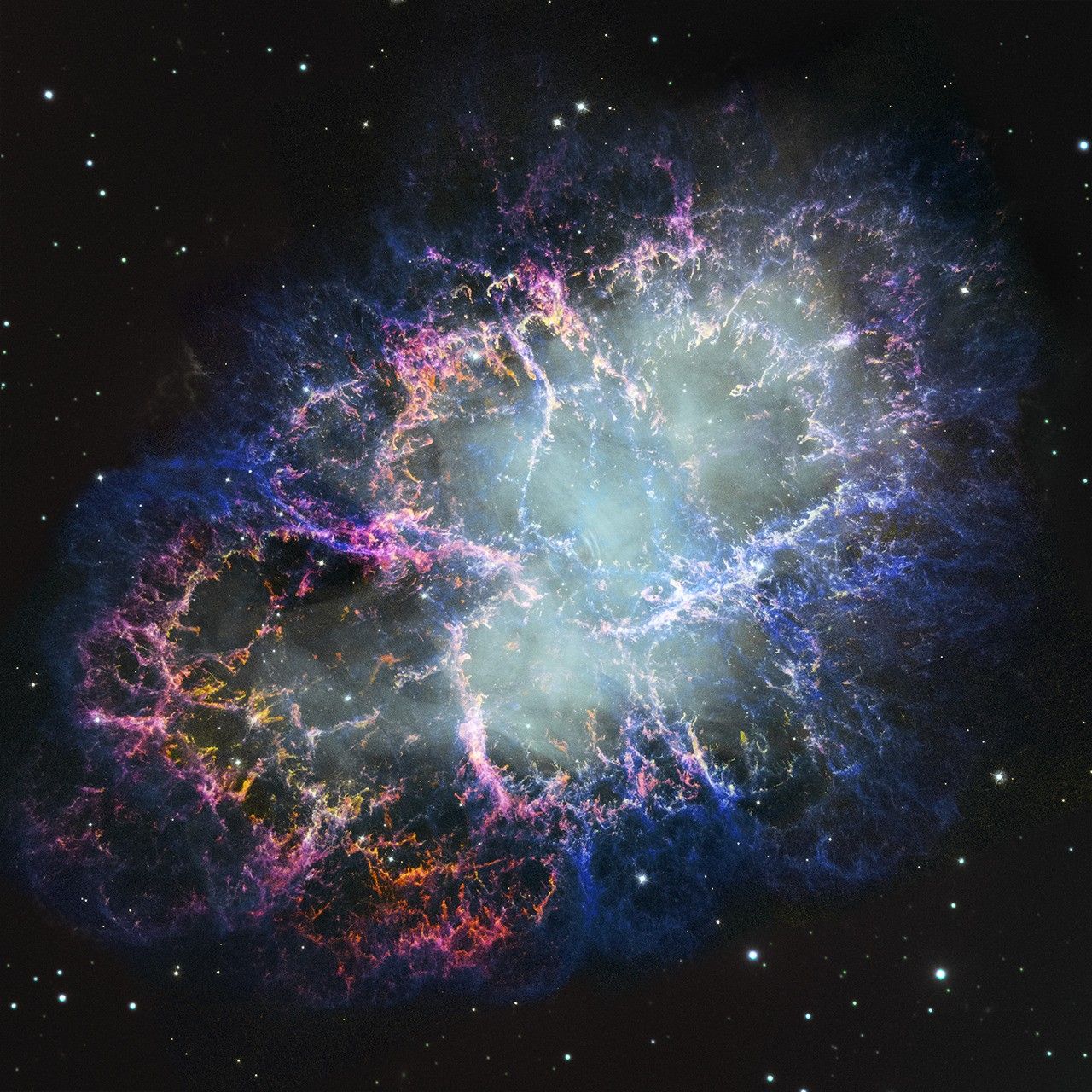 A colorful nebula of thick filaments of cosmic dust and gas appears to splash outward from a hazy white center. Colors include bright pink, blue, and orange. Small white stars dot the background.