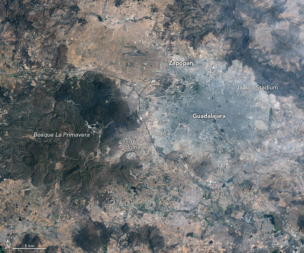 : Images of Guadalajara in 1986 (left) and 2026 (right) shows the city expanding westward into an area that had been mostly farmland. Guadalajara Stadium appears as a small circular feature on the left side of the 2026 image.